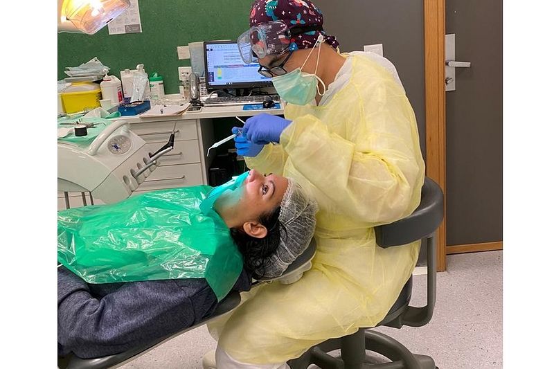 林宗億(著黃色隔離衣者)說他們牙醫系一共要念5年,3年級開始就要臨床實作,在教授監督下為患者洗牙。(林宗億提供)