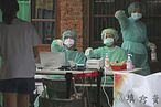 5月18日，台灣疫情警報升至第三級，醫護人員穿著防護裝備在快篩站工作。（AP）