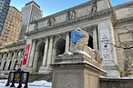 紐約市立圖書館前的獅子石像，也戴上了口罩。（陳芃彣提供）