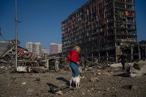 烏克蘭戰爭：基輔市民 Irina Zubchenko 與她的狗兒行經被炸成廢墟的購物中心前。（AP）
