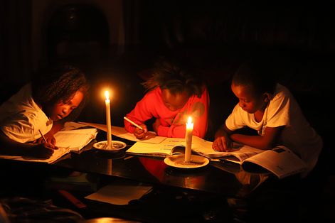 辛巴威是全球通膨最嚴重的國家之一，全國還面臨大規模停電，在首都哈拉雷（Harare）孩子們只能就著燭光寫作業。（AP）