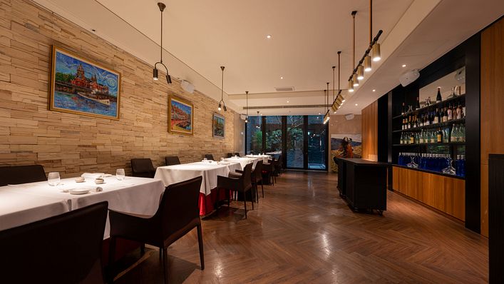 渥達尼斯磨坊空間設計一區延續西班牙本店百年磨坊的石牆風格,大片落地窗與室外百年連結。(圖片來源/慕舍酒店 提供)