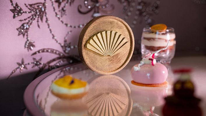 巧克力焦糖堅果瑪德蓮: 外層以 58%黑巧克力製成,口感酥脆,中間夾入杏仁與榛果醬,底部則搭配焦糖瑪德蓮,外型製成酒店集團標誌性的摺扇,整體帶有醇厚的焦糖與黑巧克力香氣。(圖/台北文華東方酒店 提供)